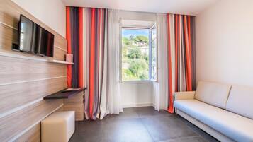 Una sala de estar moderna con un televisor de pantalla plana, un sofá, un banco y una ventana con cortinas.