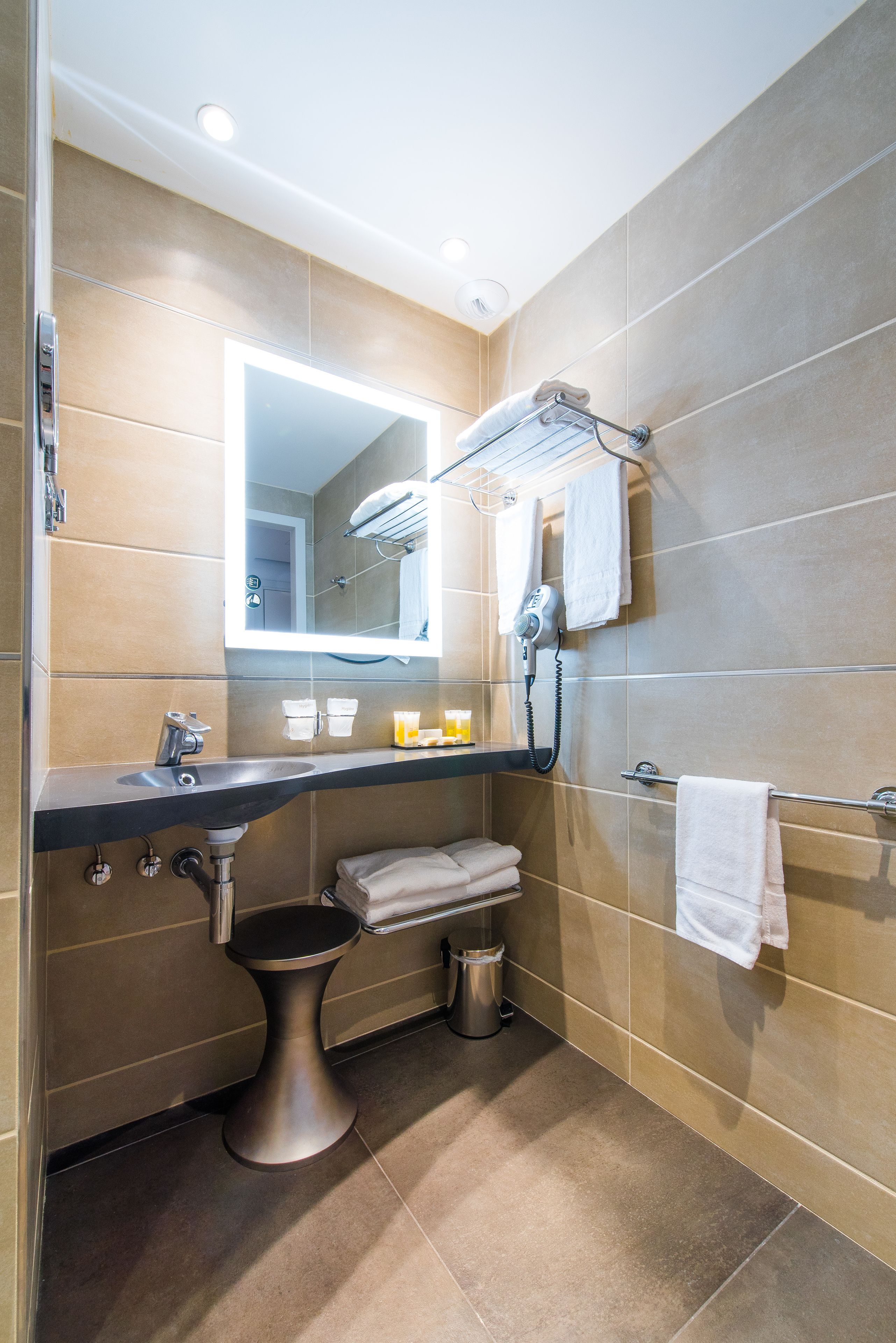Casa de banho moderna com toucador, lavatório, espelho, suporte para toalhas e secador de cabelo.