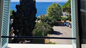 A balcony with a view of the sea, trees, and parked cars. - Le Saint Paul Hôtel (Nice)