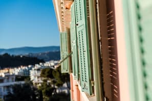 A building with green shutters and a view of a cityscape in the background.