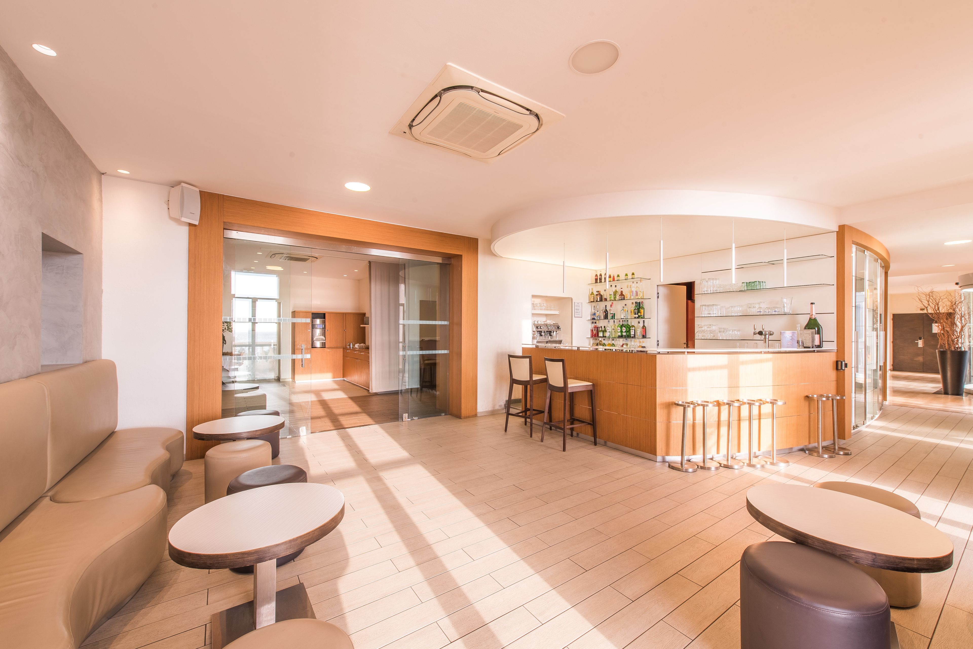 Een modern interieur met een bar, zitgedeelte en een keuken op de achtergrond.