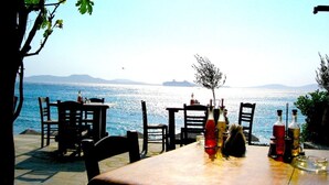 An outdoor dining area with tables and chairs facing a body of water. - Amalia Residences (Marathon)