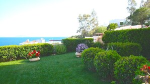 A well-maintained garden with various plants and a view of the sea. - Amalia Residences (Marathon)