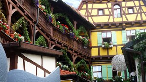 A traditional half-timbered building with balconies adorned with flowers, a reception area, and a clear sky. - Hezelhof Hotel (Dinkelsbuehl)