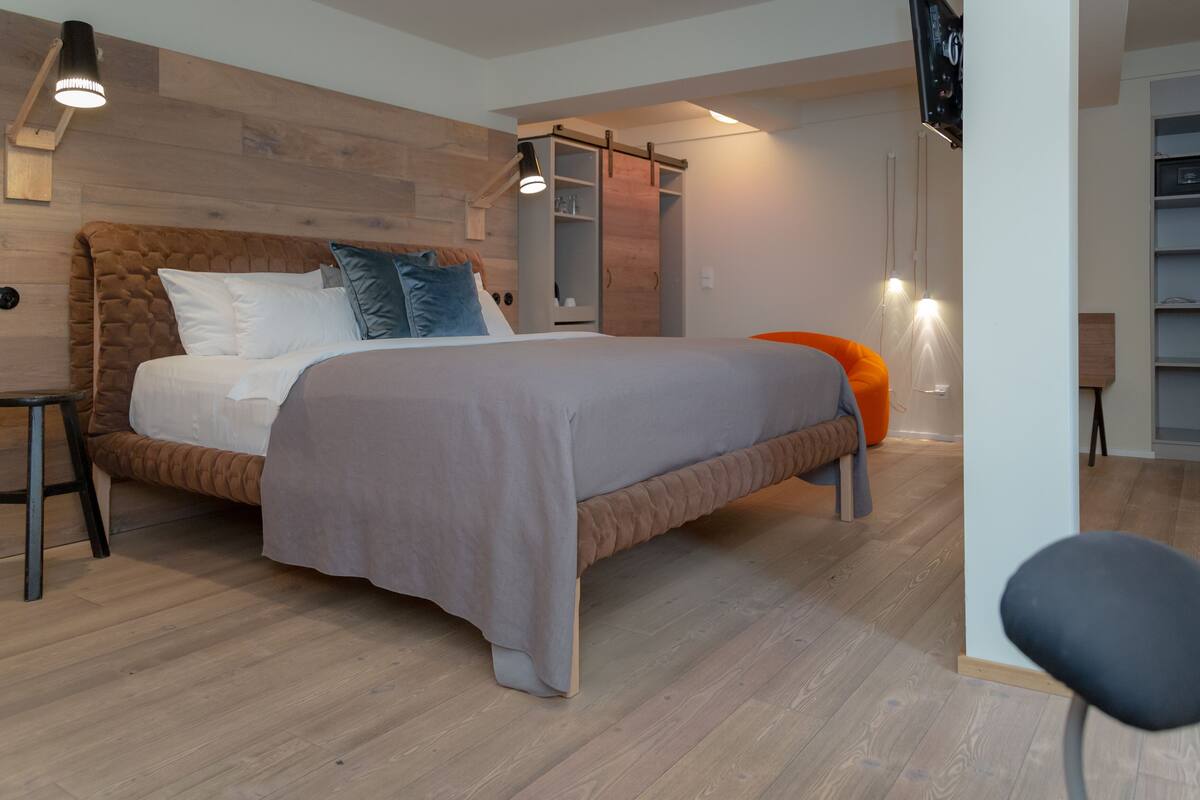 A modern bedroom with a large bed, wooden headboard, and a sliding closet.