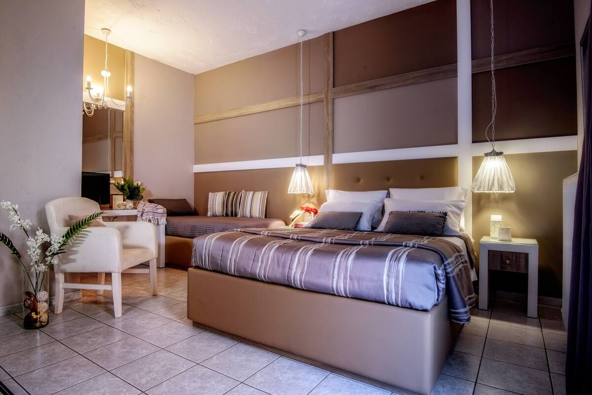 Um quarto moderno com uma cama grande, uma mesa de cabeceira, uma cadeira e uma pequena mesa com abajur.