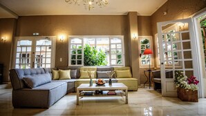 A spacious living room with a sectional sofa, a coffee table with books, and a chandelier. - Hotel Lino Mare (Malevizi)