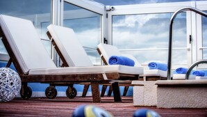 A deck with two lounge chairs, a small sink, and a large window. - Hotel Lino Mare (Malevizi)