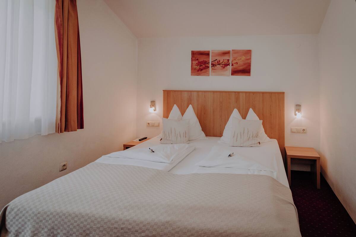 Een hotelkamer met een groot bed, twee nachtkastjes, een houten hoofdbord en drie wandlampen.