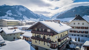 Un pueblo cubierto de nieve con arquitectura alpina tradicional, incluyendo edificios de varios pisos con balcones y diversos estilos de ventanas.