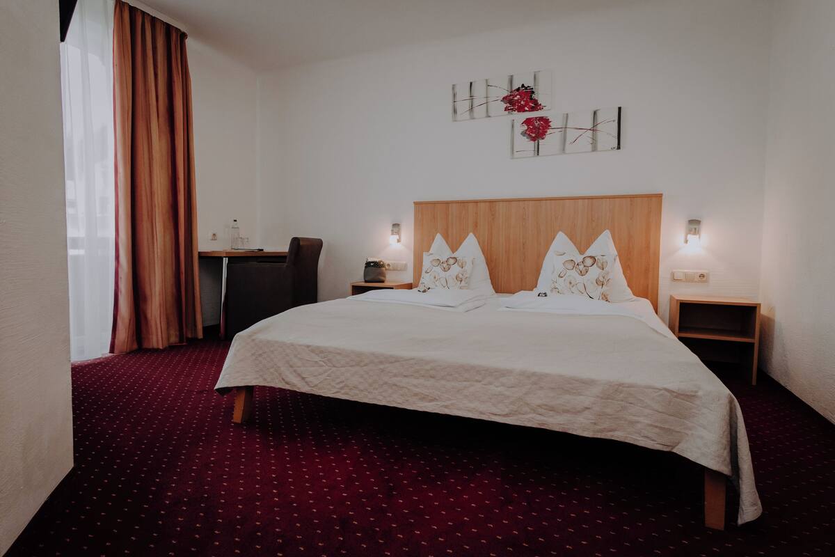 Een hotelkamer met een groot bed, een bureau en twee nachtkastjes.