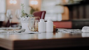 Una mesa de comedor con un jarrón blanco que contiene una planta, saleros y pimenteros, y un candelabro.