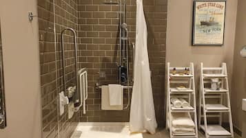 Un baño con ducha, un perchero blanco y un cartel en la pared.
