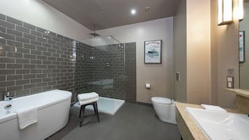 A modern bathroom with a glass-enclosed shower, a white bathtub, and a toilet.