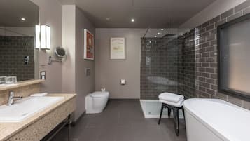 Een moderne badkamer met een grote spiegel, een wastafel, toilet, douche en een bad.
