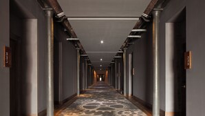 A long, narrow hallway with a patterned carpet, metal columns, and doors on either side. - Titanic Hotel Liverpool (Liverpool)