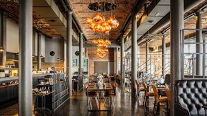A spacious dining area with high ceilings, exposed brick walls, and a modern chandelier. - Titanic Hotel Liverpool (Liverpool)