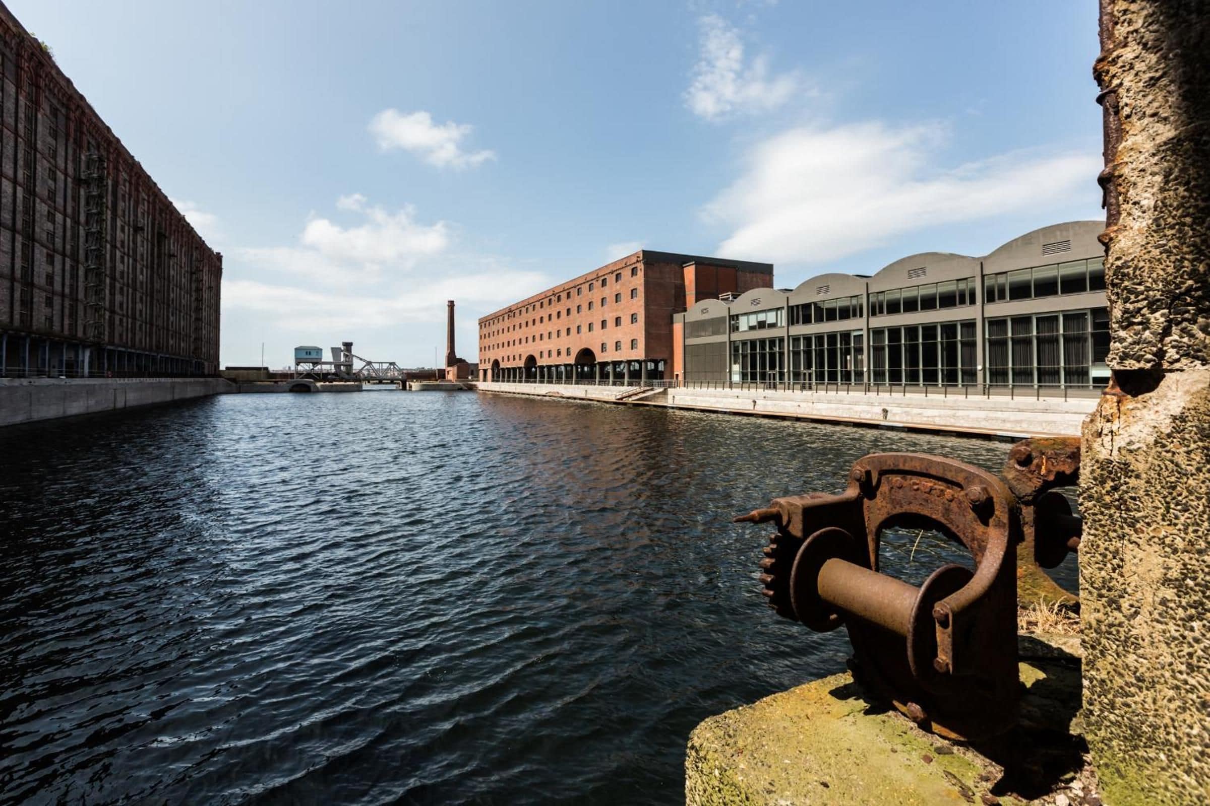 Un canal doté d’une écluse, un bâtiment en briques et une structure moderne avec de grandes fenêtres.