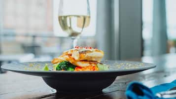 Un plato de comida con una copa de vino blanco sobre una mesa.