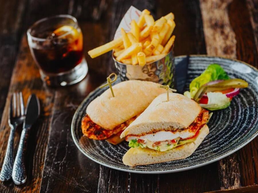A sandwich with a side of fries and a drink on a plate.