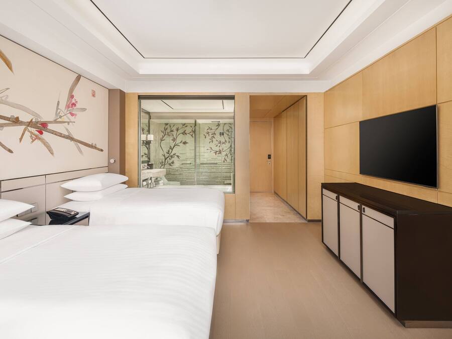 A hotel room with two beds, a TV, and a wooden cabinet.