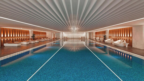 A modern indoor swimming pool with a long, narrow design, surrounded by seating areas with wooden paneling and white cushioned loungers. - Shanghai Marriott Hotel Parkview (Shanghai)