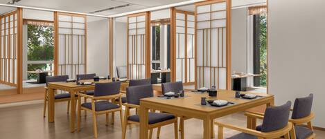 A conference room with wooden tables and chairs, large windows, and a view of greenery outside.
