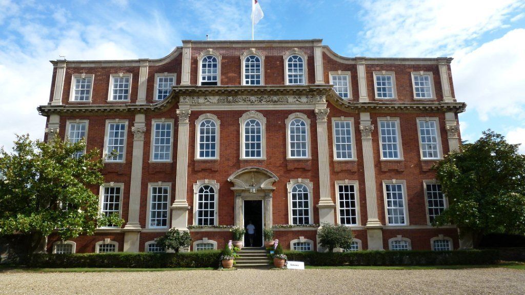 A large, red-brick building with a symmetrical facade, multiple windows, and a central entrance.