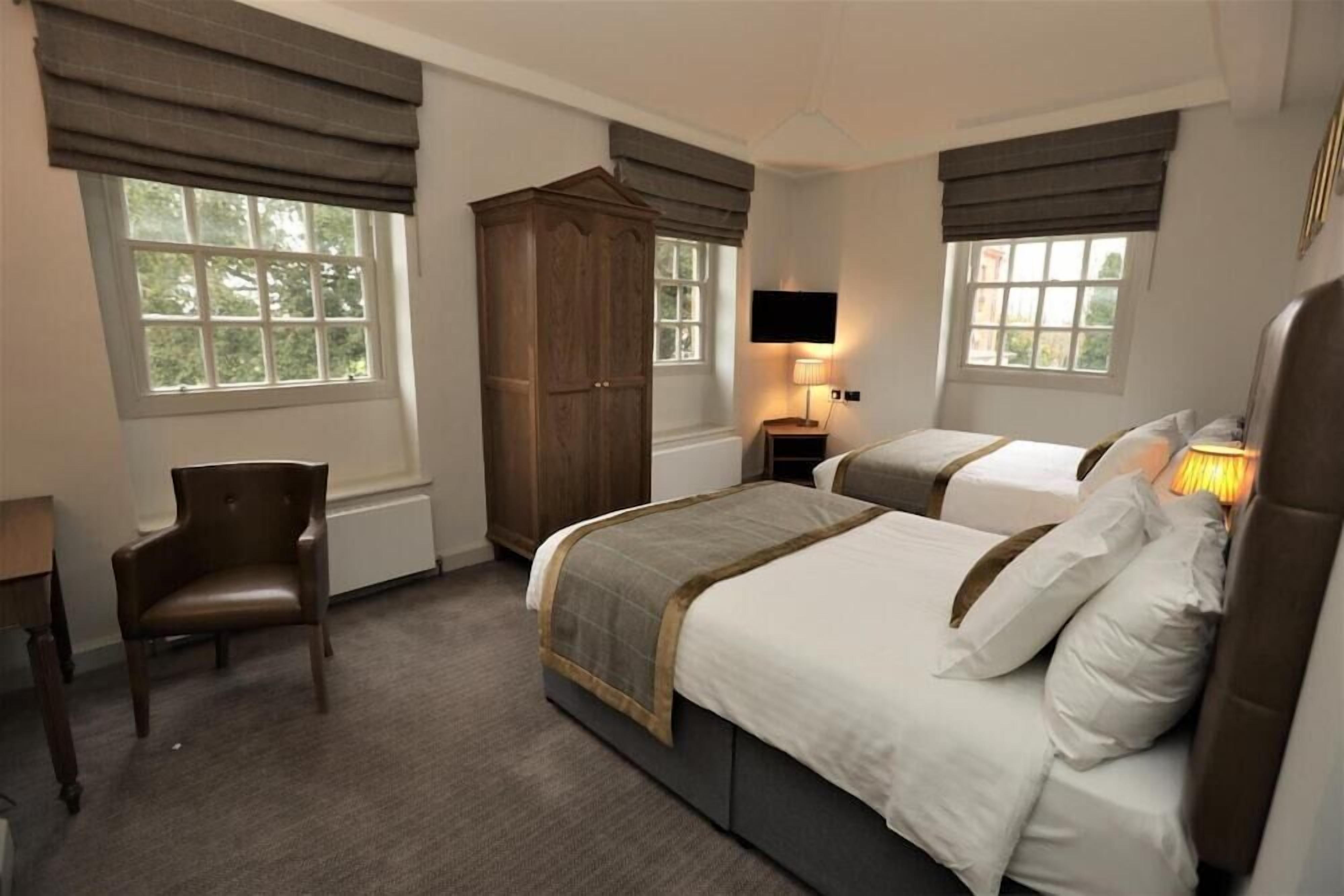 Une chambre d’hôtel avec deux lits, une armoire en bois, un bureau et une chaise.