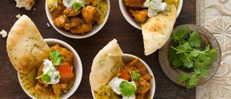 Una mesa con alimentos, incluyendo arroz y pan, y un tazón pequeño de hierbas frescas.