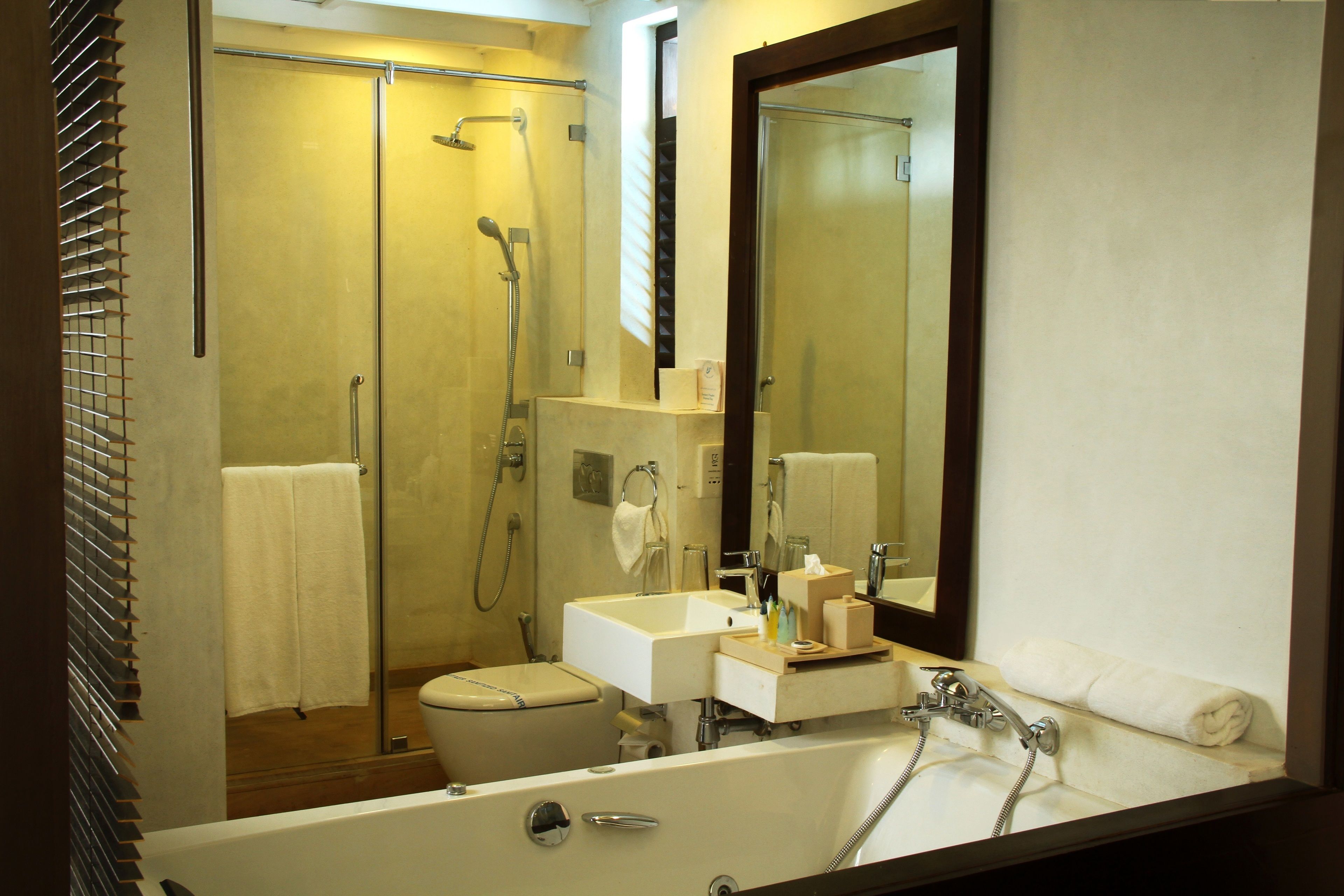 Une salle de bain équipée d’une douche, de toilettes, d’un lavabo et d’un grand miroir.