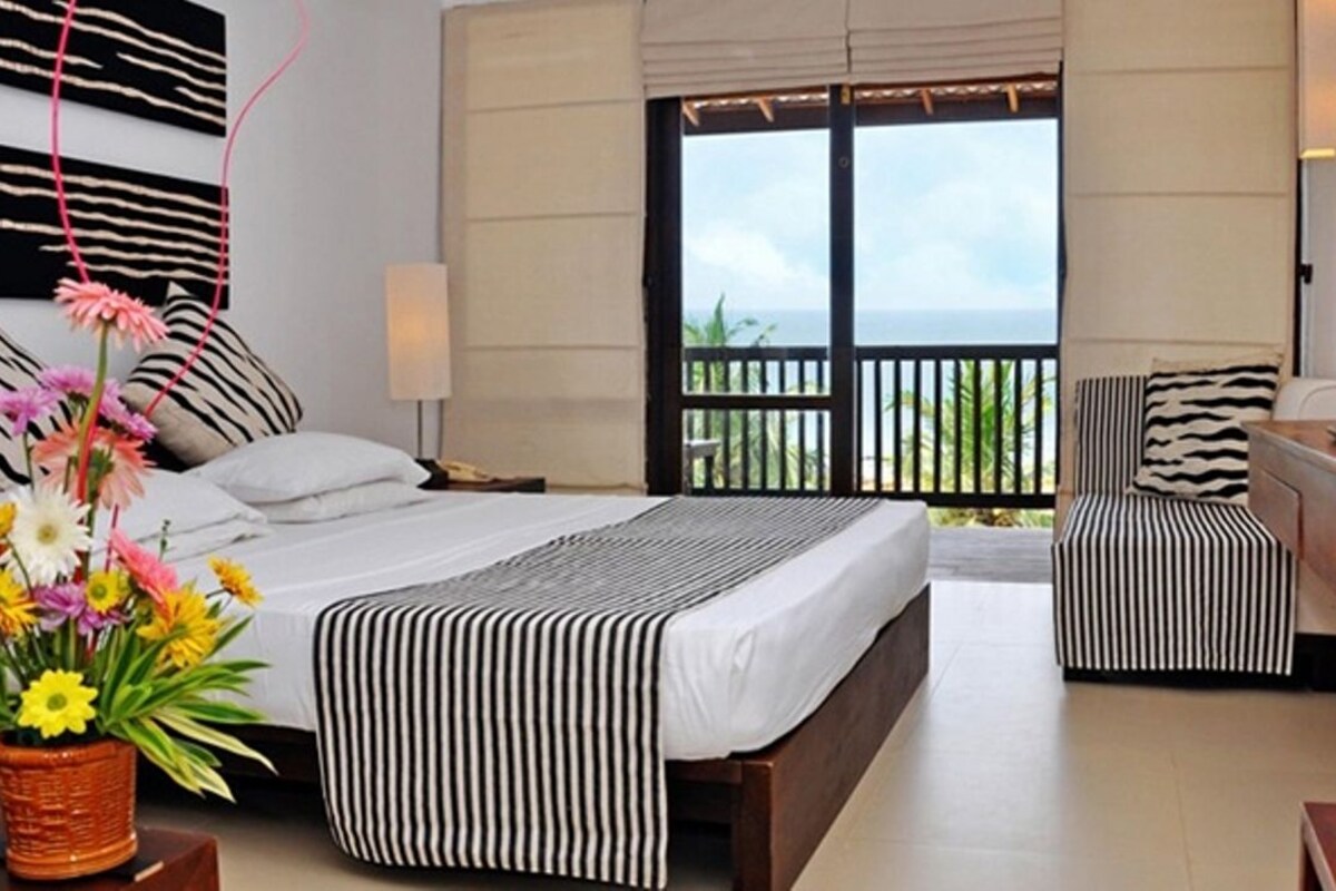 A hotel room with a bed, a TV, a desk, and a balcony with a view.