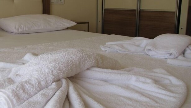Una cama bien hecha con sábanas y toallas blancas.