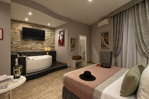 A modern bedroom with a large bed, a wall-mounted TV, a bathtub, and artwork on the walls. - Five Rooms Rome Guesthouse (Rome)
