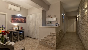 A modern kitchen with a wine fridge, a dining area with a table and chairs, and a staircase leading to another level. - Five Rooms Rome Guesthouse (Rome)