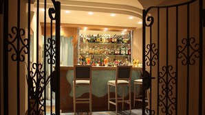 An interior bar area with a bar counter, multiple liquor bottles, and two bar stools. - Hotel Bellevue Benessere & Relax (Ischia)