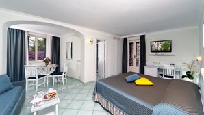 A hotel room with a bed, a desk, a chair, a TV, and a window with curtains. - Hotel Bellevue Benessere & Relax (Ischia)
