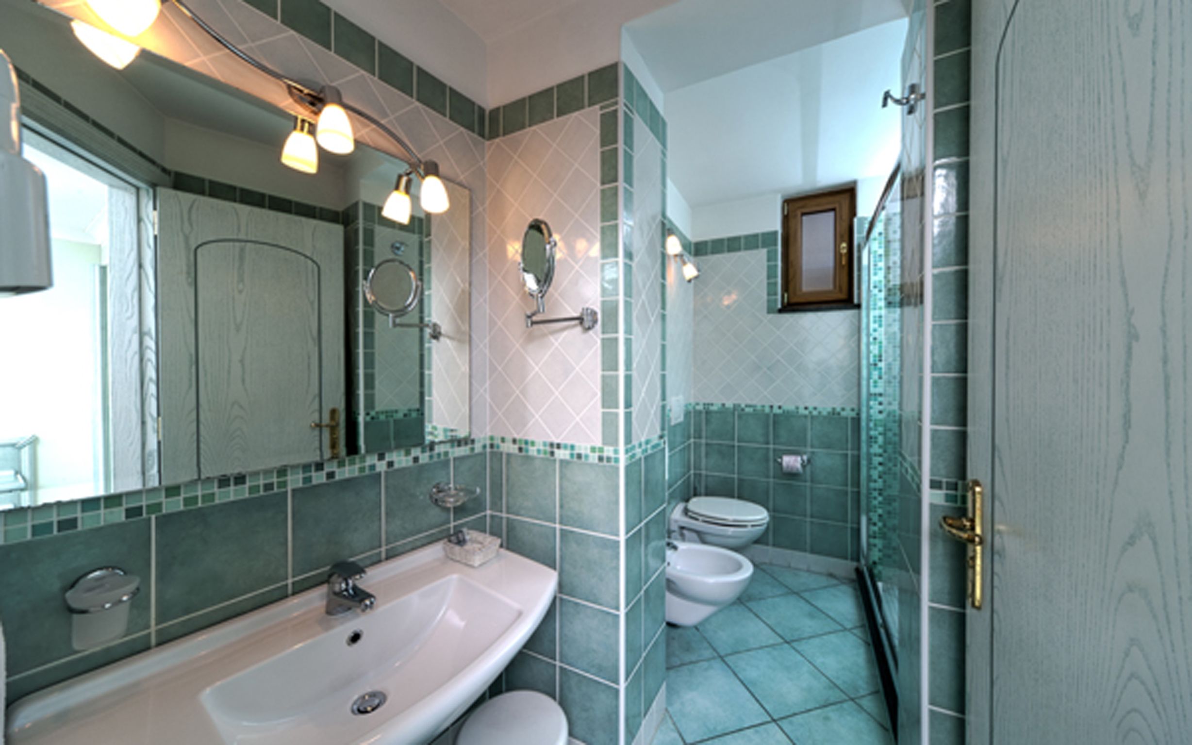 A bathroom with a sink, two toilets, a mirror, and a shower.