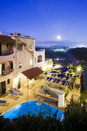 A hotel with a swimming pool, lounge chairs, and a view of the surrounding landscape. - Hotel Bellevue Benessere & Relax (Ischia)