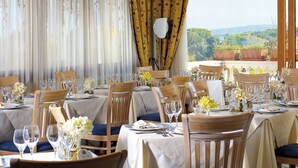 A restaurant with multiple tables set for dining, each with chairs, wine glasses, and floral centerpieces. - Hotel Bellevue Benessere & Relax (Ischia)