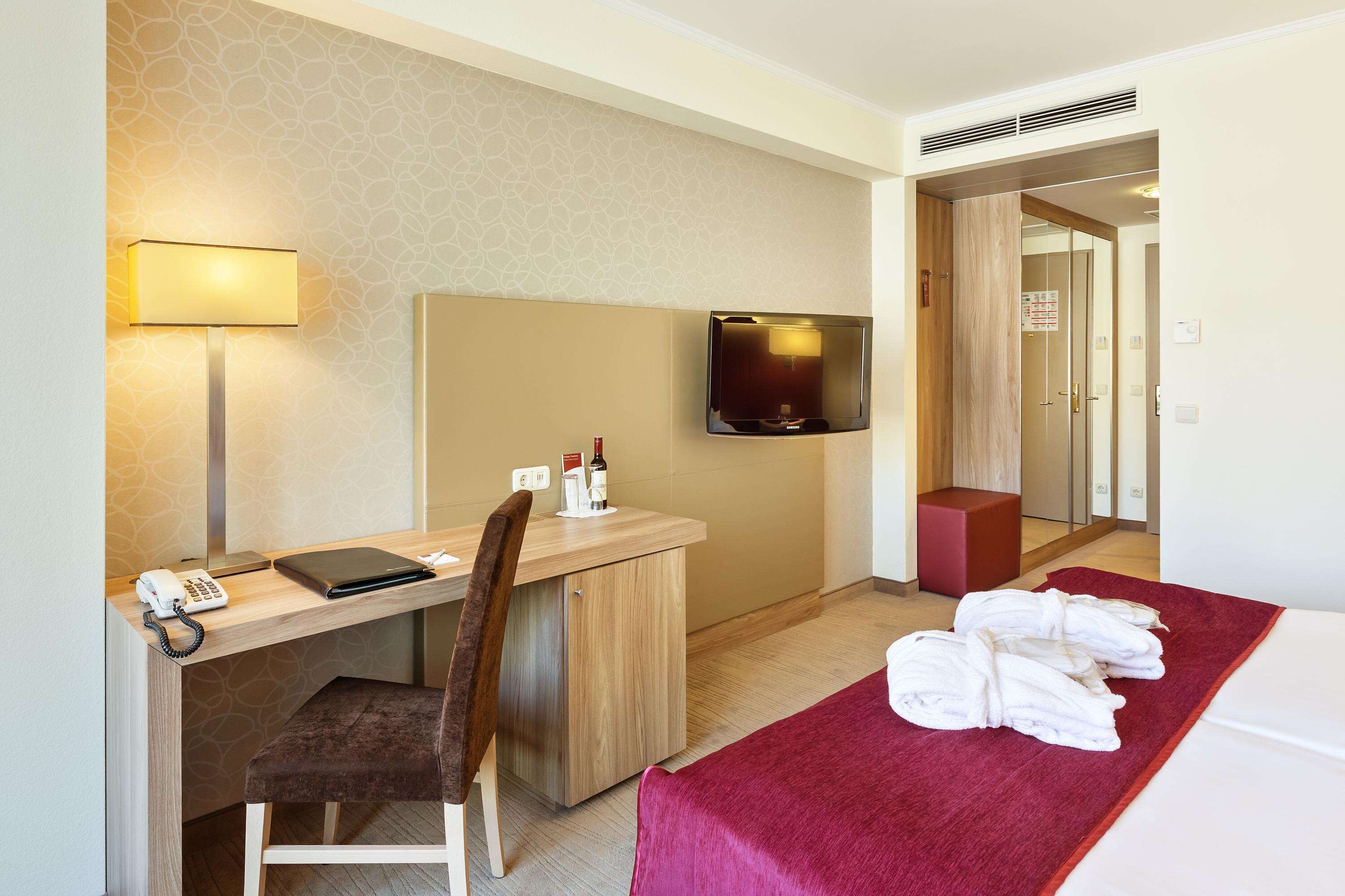 Une chambre d’hôtel équipée d’un bureau, d’une chaise, d’une télévision et d’un lit avec des serviettes.