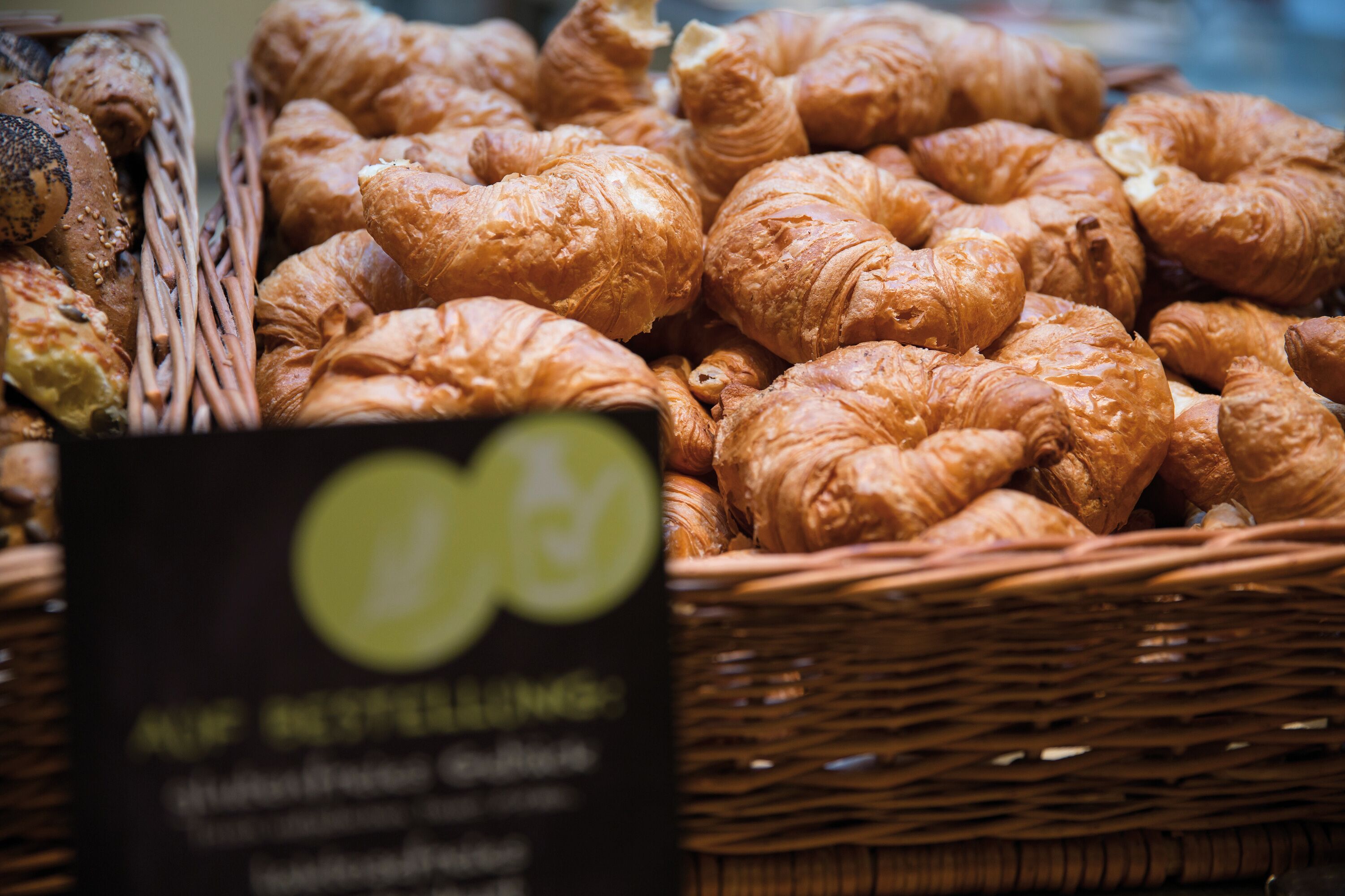 Ein Korb mit verschiedenen Backwaren, darunter Croissants und Brot, mit einem Schild, das einen Rabatt von 10% anzeigt.