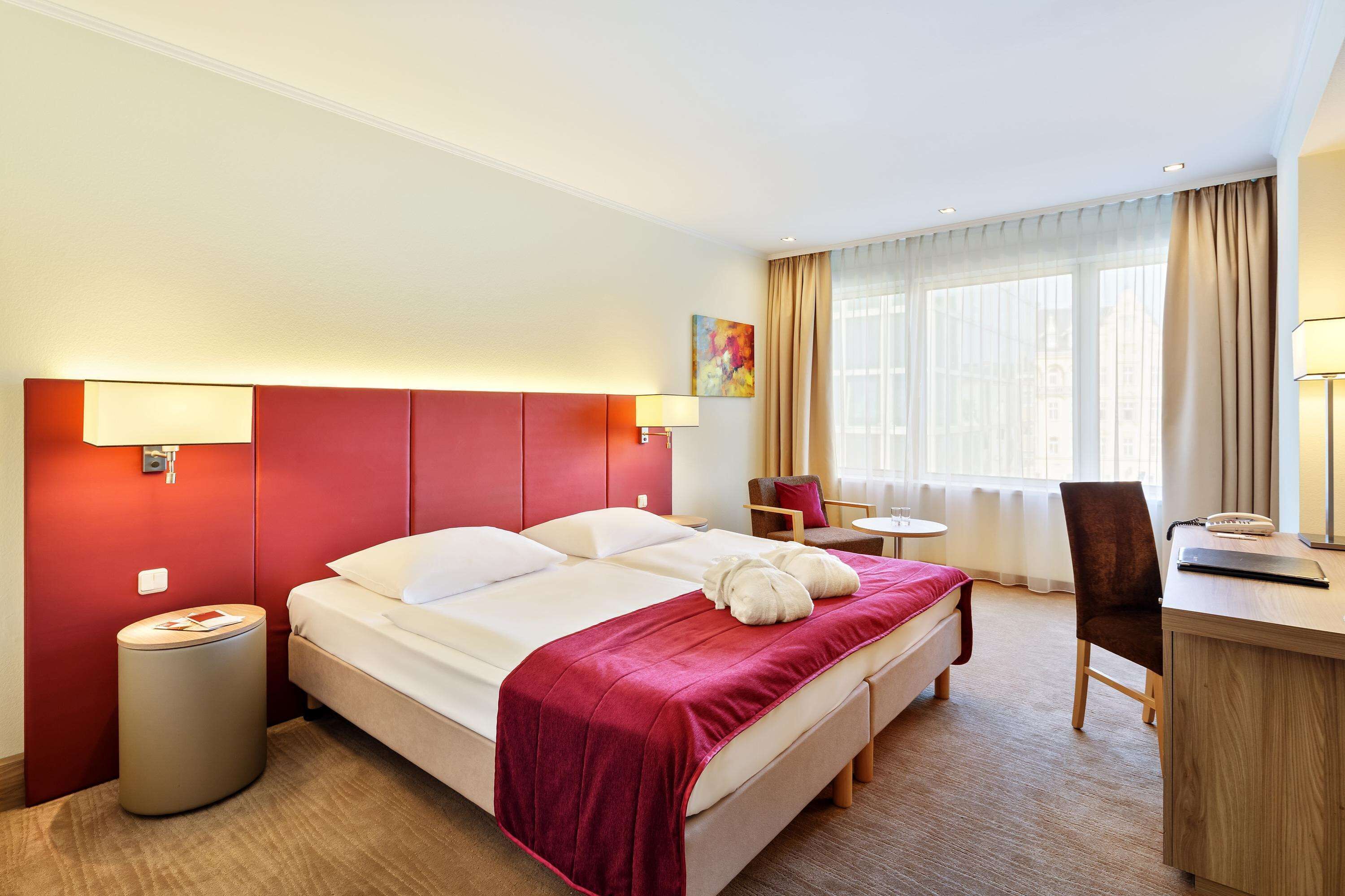 Una habitación de hotel con cama, mesitas de noche, escritorio y una silla.
