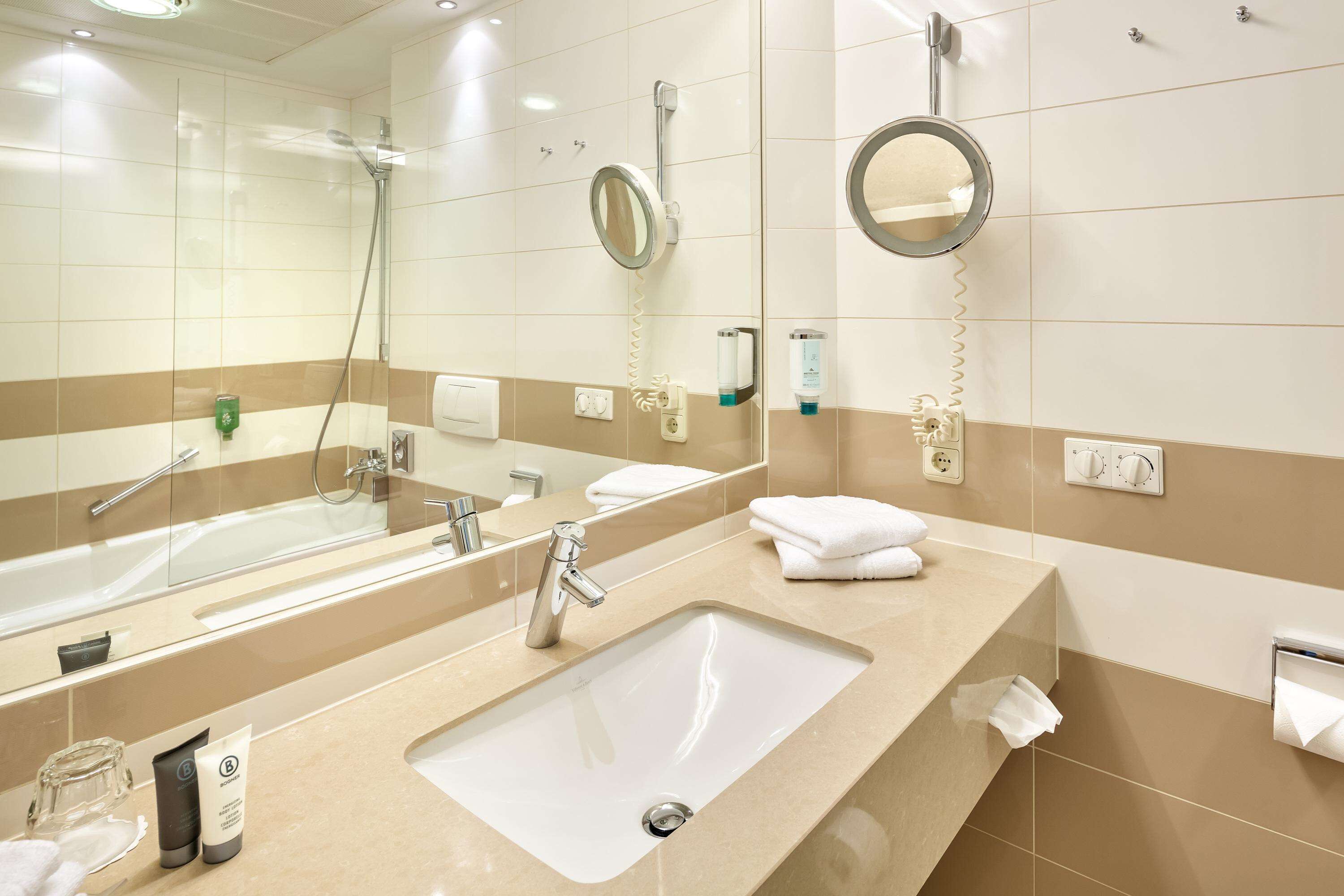 Een moderne badkamer met twee wastafels, een grote spiegel en een douche.