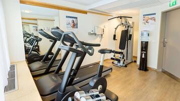 A gym with treadmills, dumbbells, and weight machines.
