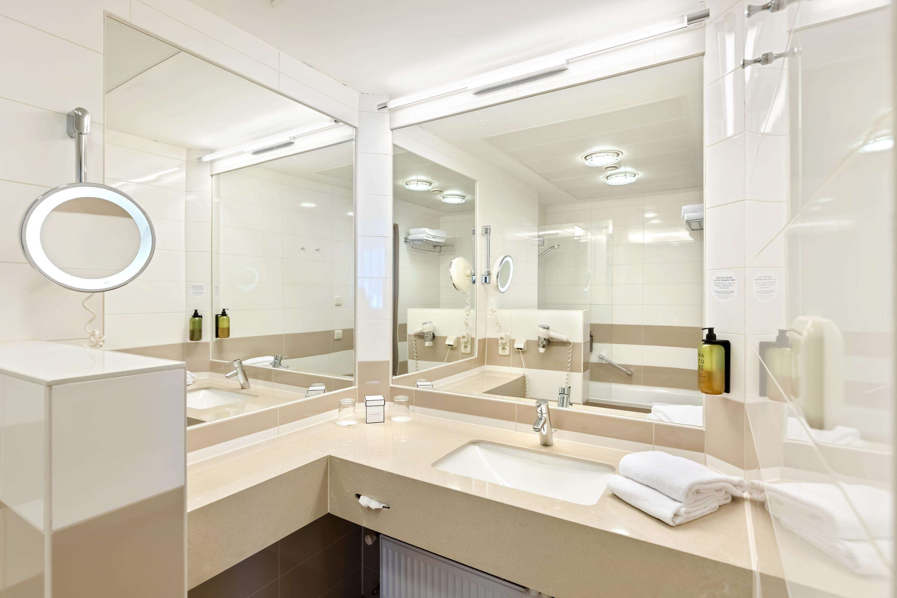 Ein modernes Badezimmer mit zwei Waschbecken, einem großen Spiegel und einer Duschkabine.