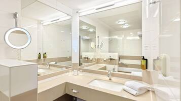 Ein modernes Badezimmer mit zwei Waschbecken, einem großen Spiegel und einer Duschkabine.