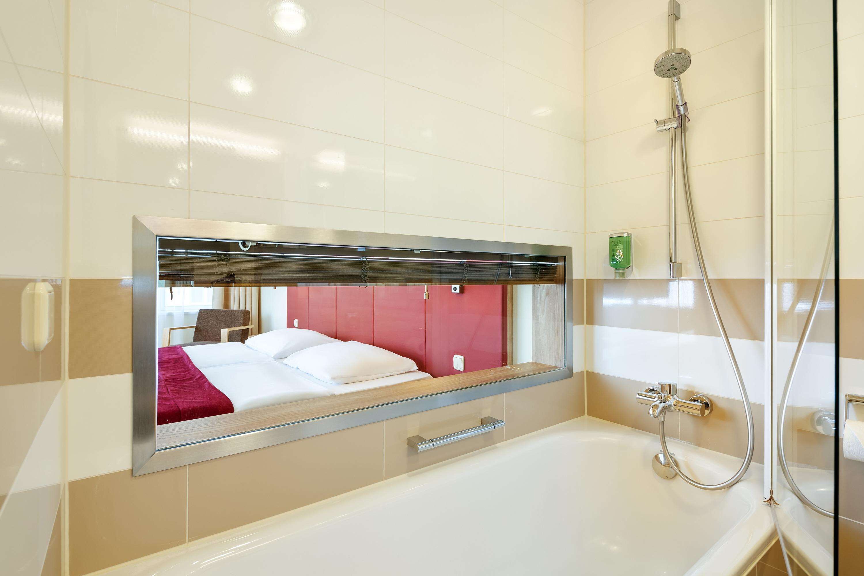 Un baño moderno con un espejo grande, una bañera y una ducha.