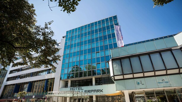 A hotel with a modern glass facade, outdoor seating area, and a restaurant named "Restaurant Tropical." - Hotel Schillerpark Linz, a member of Radisson Individuals (Linz)