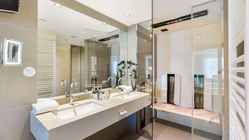 Une salle de bain moderne avec deux lavabos, un grand miroir et une douche à l’italienne.